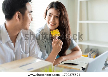 E-commerce and shopping online concept. Asian young couple buying online from website using credit card for payment. Smile woman holding credit card in hand and order during Covid19 crisis outbreak.