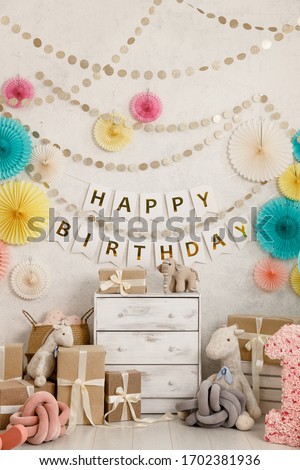Birthday decorations with balloons, gifts, toys, garlands and candy for yearling, little baby party, selebration on a white wall background. Decor elements in unicorn colors.