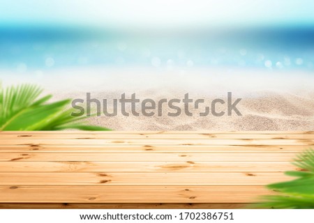 Beautiful Summer background woodent table top and blur sea sandy beach view with green plam leaves as frame