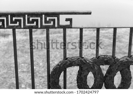 Old broken cast iron railing with classic pattern, abandoned building exterior fragment. Black and white photo