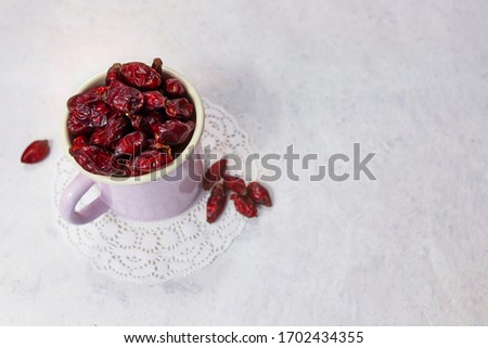 Dried rose hips in enameled mug top view on white background. Picture with  selective focus and copy space. Healthy eating concept