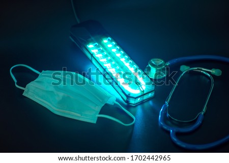 UV light sterilization of face mask to disinfect and reuse. COVID-19 prevention concept. Royalty-Free Stock Photo #1702442965