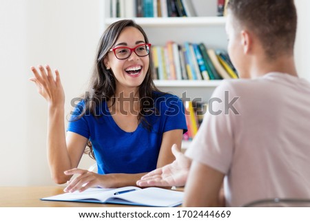 Pretty nerdy female student with eyeglasses learning with student at classroom of school Royalty-Free Stock Photo #1702444669