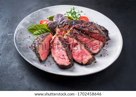 Barbecue dry aged wagyu entrecote beef steak with lettuce and tomatoes as closeup on a modern design plate Royalty-Free Stock Photo #1702458646