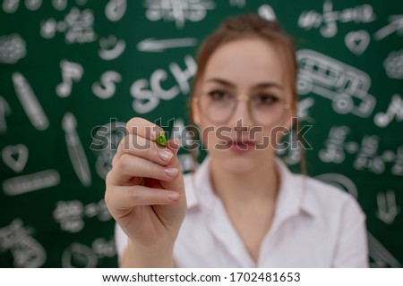 Education concept - green backpack, notebooks and school supplies on the background of the blackboard.