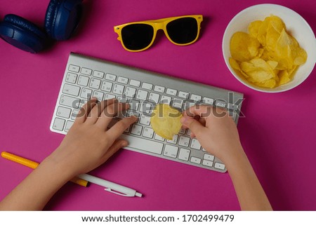 Flat lay of keyboard, headphones, sunglasses, pen, and a plate of chips in purple background. Concept of a teenager, blogger, student. Top view.