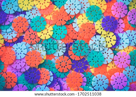 Multi-colored designer background. Multi-colored details in the form of snowflakes from the children's designer. Plastic discs for the development