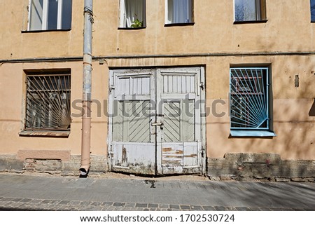 Old wooden gate on the yellow wall of a building with windows