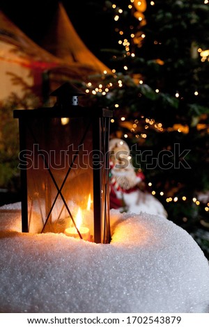 Lantern standing in the snow, Santa Claus sitting at back