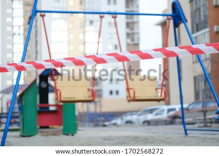 Empty swing set with caution tape to close off playground to children to help fight the coivd-19 disease. Close up empty swing set playground. Royalty-Free Stock Photo #1702568272
