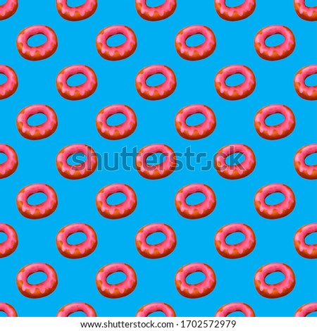 Seamless pattern with pink glazed donuts at blue background.
