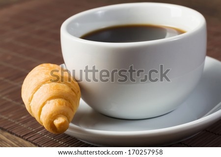 Cup of coffee and croissant on saucer