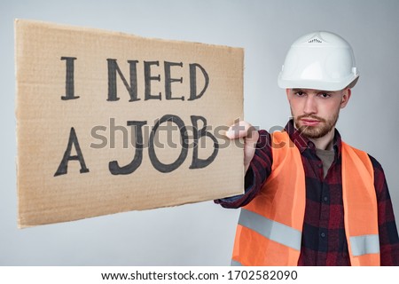 An unemployed Builder with a poster in his hands. The Builder is looking for work. Unemployment in construction.Crisis in the labor market. Dismissal of workers. Termination of the activities of firms