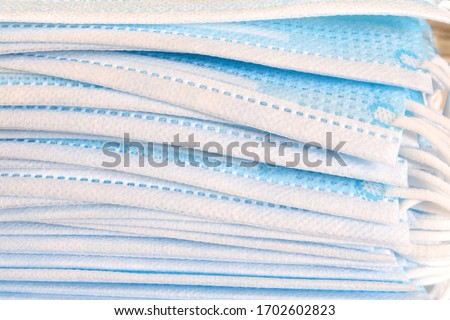 Pieces of 3 ply medical grade face mask stacked, closeup view. New supply of surgical mask piled up. Layers of blue disposable mask or protective facial cover to block viruses, germs and bacteria.