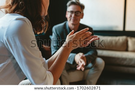 Two business people discussing in office lounge. Businesswoman talking with a male colleague in office lobby. Royalty-Free Stock Photo #1702602871