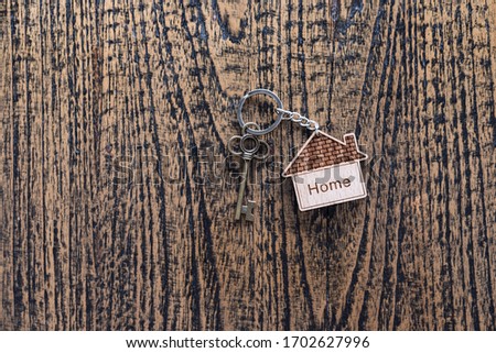 House key with home keyring decorated with mini heart on rusty wood background, copy space