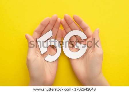 cropped view of woman holding white 5g lettering on yellow background