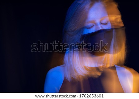 Romantic portrait creative artistic of young blonde woman in face mask. Black, blue and orange colors. closed eyes. relaxed and tired. respiratory breathing polluted air. epidemic panic pandemic.  