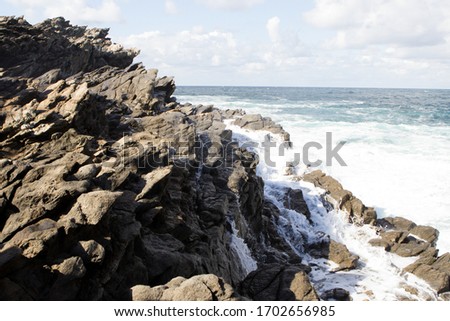 Amazing view on the blue sea near La Pelosa Beach. Sunny rocks, waves with foam and water splashing in Stintino, Sardinia, Italy