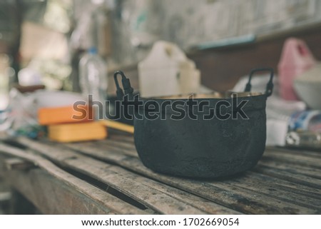 An old pot placed on a table made of bamboo.