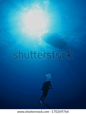Boat and diver silhouette under water with beautiful sun ray, Hawaii.
