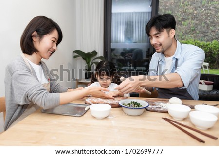 Young Asian mom and dad making dumplings with daughter