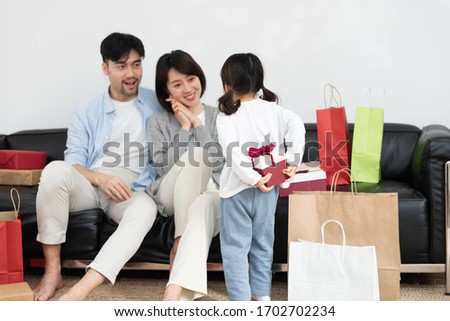 Young Asian mom and dad are unpacking gifts with their daughter