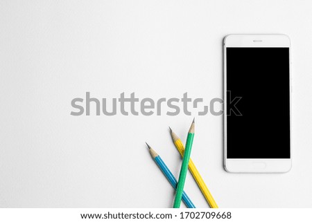 Mobile phone and Pencil on white wooden desk. Top view. Free place for text.