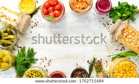 Background of food stocks in glass jars. Pickled vegetables and mushrooms. Top view.