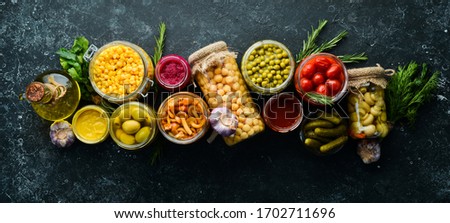 Food stocks in glass jars. Pickled vegetables. On a black background. Top view.