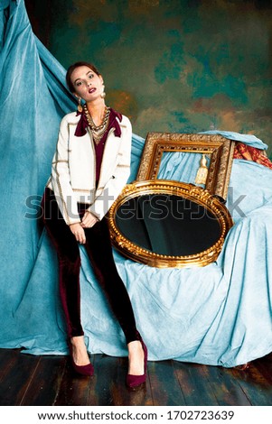 beauty rich brunette woman in luxury interior near empty golden frames, lifestyle people concept