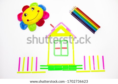 Bright colored rainbow from pencils, a house of bright colored sticks on a white background