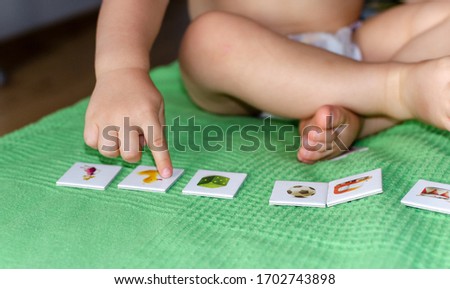 Child lining up toys on the floor at home. Kids education concept.