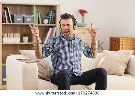 Handsome young man sitting on his sofa and listening to music  