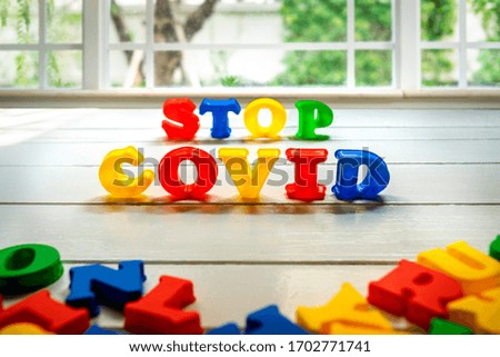 Stop Covid-19 Sign & Symbol, plastic letter on white wood background