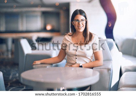 Young beautiful woman smiling happy and confident. Sitting with smile on face at bar