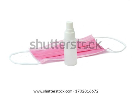Spray bottle in front of pink earloops face mask. safety breathing medical mask on white background