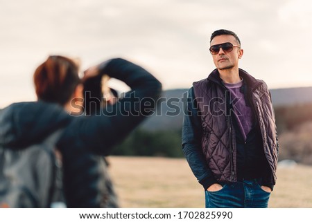 Woman photographing her boyfriend while hiking