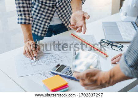 engineer Hand Drawing Plan On Blue Print with architect equipment discussing the floor plans over blueprint architectural plans at table in a modern office