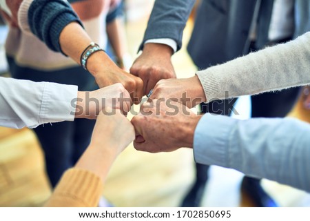 Group of business workers standing bumping fists at the office Royalty-Free Stock Photo #1702850695