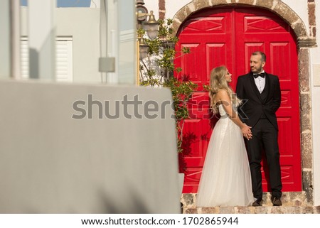 Happy wedding couple posing in front of big red door