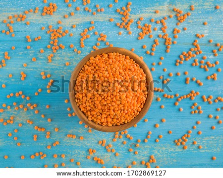 Red Lentils or Masoor Dal in wooden bowl on light blue background. Top view. Flat lay. Colorful and stylish composition. Vegetarian super food. Healthy eating and dietary. Canadian Orange Lentil Royalty-Free Stock Photo #1702869127