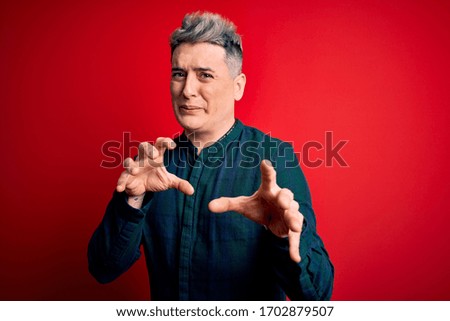 Young handsome modern man wearing elegant green shirt over red isolated background disgusted expression, displeased and fearful doing disgust face because aversion reaction.