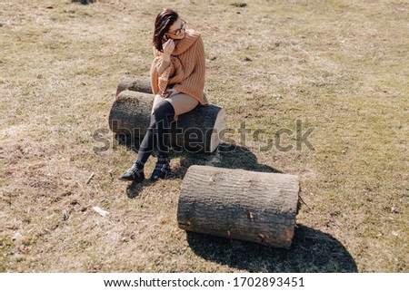 young attractive stylish girl on nature on forest background with phone on a sunny day. outdoor holidays and dependence on technology, internet.
