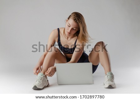 athletic girl posing in the Studio performing exercises online on a laptop on a white background