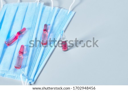 Surgical masks for cover mouth and nose and red vaccine on gray background. Concept of protection, virus epidemic or pandemic, corona virus, covid-19
