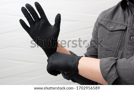 Man puts on black nitrile medical gloves