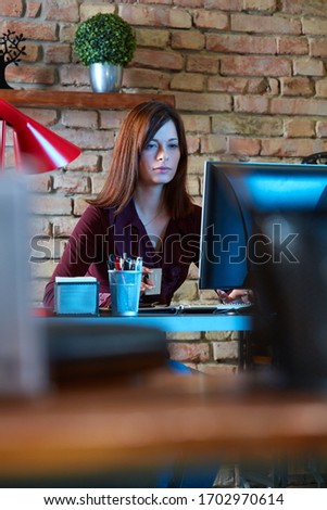 Young businesswoman working from home using computer, sitting at desk.
