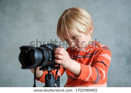 Boy plays with professional photo camera in studio