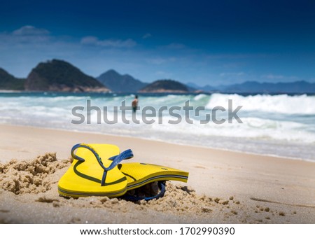 A man leaves his flip flops on sands of Copacabana Beach while going for a swim in the oceans of Rio de Janeiro, Brazil.